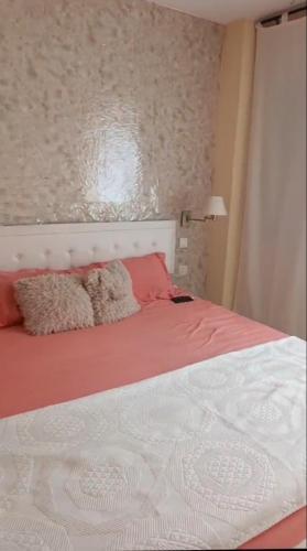 Schlafzimmer mit einem Bett mit rosa und weißer Bettwäsche in der Unterkunft Piso en Estación de buses in Granada