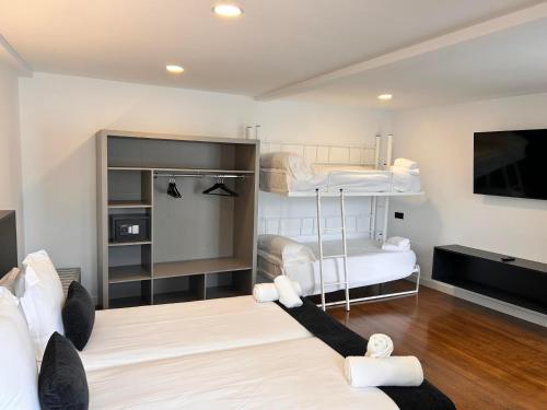 a room with two bunk beds and a flat screen tv at APARTAMENTOS NADA Ó NORTE Centro in Viveiro