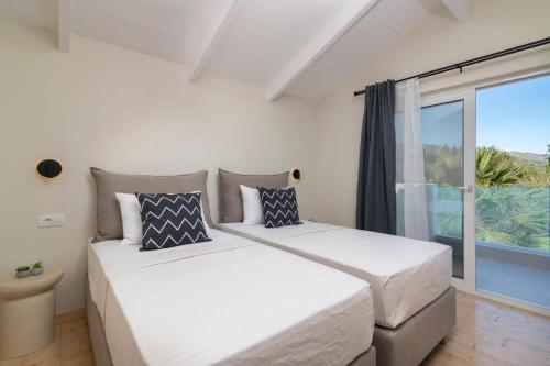 two beds in a bedroom with a large window at Villa Zante Pnoe by Villa Plus in Pandokrátor