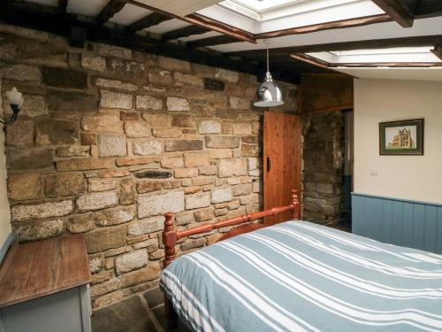 a bedroom with a stone wall and a bed at The Goat Shed in Hawsker