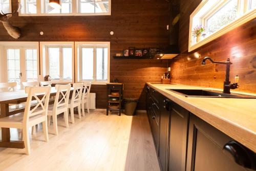 a kitchen with a sink and a table with chairs at Utsikten - Ny flott hytte, Privat Badstue, Spabad! in Torsby