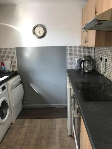 eine Küche mit Waschmaschine und Trockner und eine Uhr an der Wand in der Unterkunft 2or3 double bedrooms apartment free parking in Edinburgh