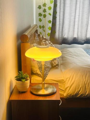 a yellow lamp on a table next to a bed at Royal fikiri house in Birmingham
