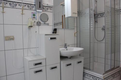 y baño blanco con lavabo y ducha. en REGIOHOTEL Aparthotel Wernigerode, en Wernigerode