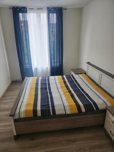 a bed with a striped comforter in a bedroom at Chambre disponible in Brussels