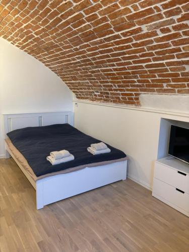 a bedroom with a bed and a brick wall at Hubane apartment Tartu kesklinnas in Tartu
