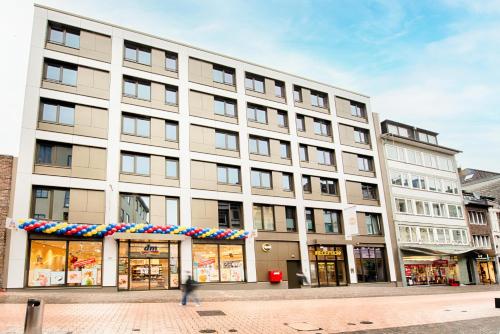 ein großes weißes Gebäude in einer Stadtstraße in der Unterkunft B&B Hotel Aachen-City in Aachen