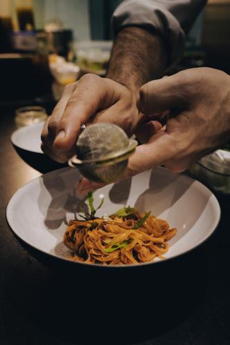 a person holding a clam on a plate of food at Palazzo Petrvs in Orvieto