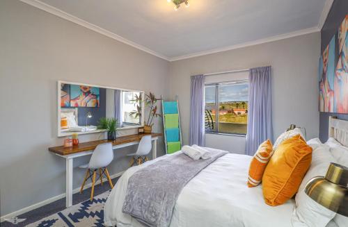 Schlafzimmer mit einem Bett, einem Schreibtisch und einem Fenster in der Unterkunft Madriko 23 - Spacious Midtown Langebaan Beach Apartment in Langebaan