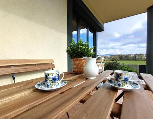 a wooden table with two cups and a vase on it at Casa de campo en Ribadeo in Ribadeo