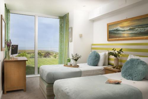 a hotel room with two beds and a window at Mermaid's Secret, Carbis Bay in Carbis Bay