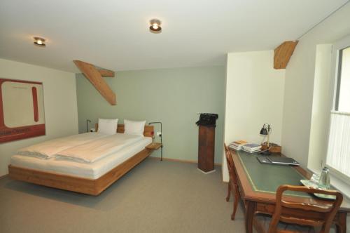 a bedroom with a bed and a desk with a desk at Hotel Restaurant Croix Blanche in Sugiez