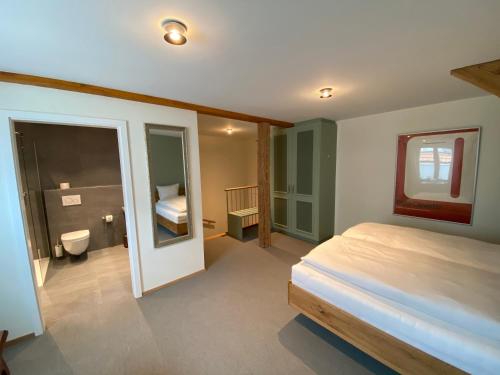 a bedroom with a bed and a bathroom with a toilet at Hotel Restaurant Croix Blanche in Sugiez