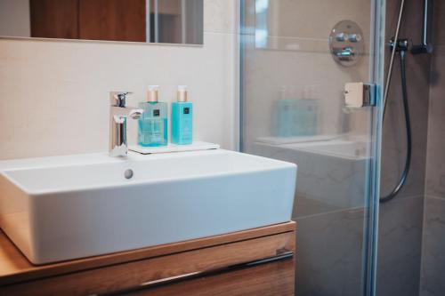 a bathroom with a white sink and a shower at MOLO LIPNO RESIDENCE in Lipno nad Vltavou