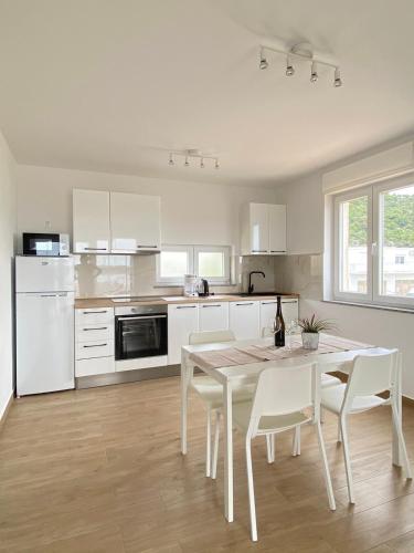 a white kitchen with a table and white chairs at Martina in Rab