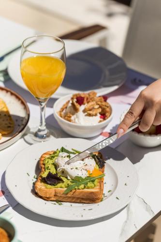a table with a plate of food and a glass of orange juice at Eliza Hotel by Panel Hospitality in Nei Poroi