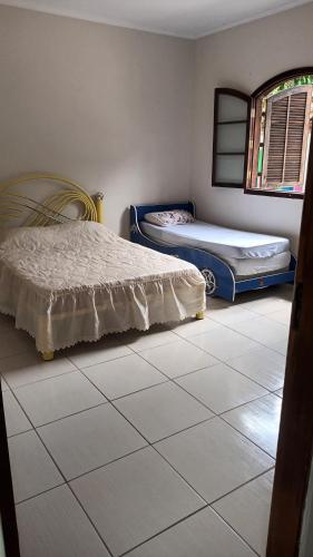 1 Schlafzimmer mit 2 Betten und Fliesenboden in der Unterkunft Chácara Tavares em São Roque in Taxaquara