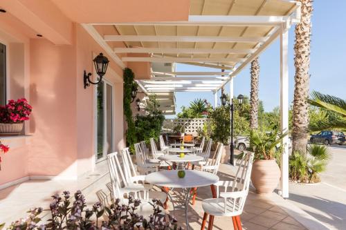 a patio with tables and chairs and palm trees at Eliza Hotel by Panel Hospitality in Nei Poroi