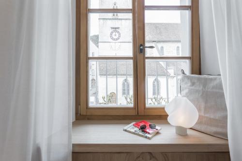 a window with a book and a lamp on a window sill at Hôtel de La Cigogne in Saint-Ursanne