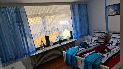 a bedroom with two beds and a window with blue curtains at Landgang in Wittdün