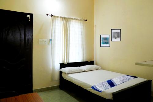 Dormitorio pequeño con cama y ventana en Kochu Mariya Residency en Punalūr