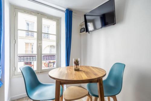 une salle à manger avec une table en bois et des chaises bleues dans l'établissement 1d Studio Central Paris Sébastopol République, à Paris