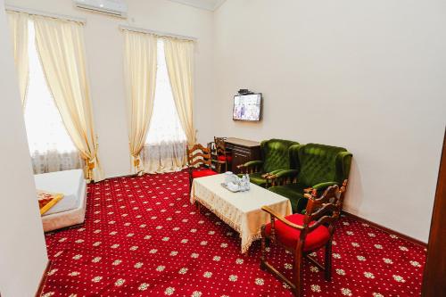 a living room with a table and green chairs at Yangi Sharq in Samarkand
