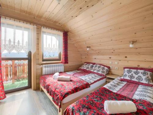 a bedroom with two beds in a wooden cabin at Nowy domek w Pieninach in Grywałd