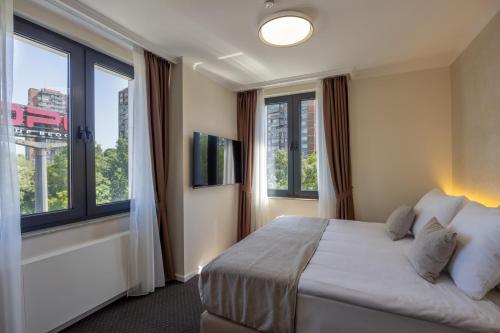 a bedroom with a large bed and large windows at Nobel West Hotel in Belgrade