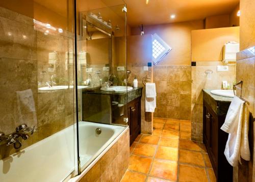 ein Badezimmer mit zwei Waschbecken, einer Badewanne und einer Dusche in der Unterkunft CORTIJO LANDETE in Granada