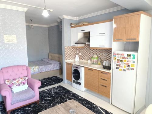 een kleine keuken met een roze stoel en een koelkast bij Egepar Rezidance Apart in Buca