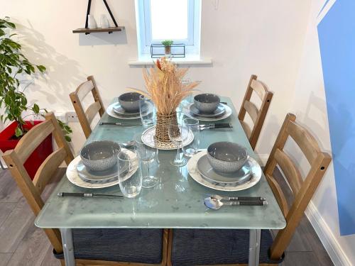 a green table with plates and bowls on it at Forsyth Court Apartment - Two bedroom in Dagenham