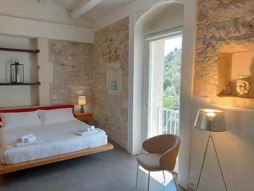 um quarto com uma cama, uma cadeira e uma janela em Itria Palace em Ragusa
