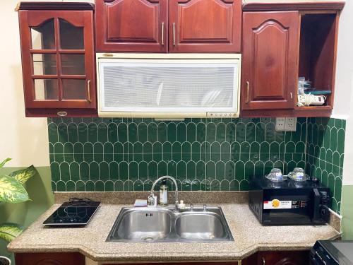 a kitchen with a sink and a green tiled wall at A Little Saigon in Ho Chi Minh City