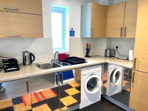 a kitchen with two washing machines and a sink at Forsyth Court Apartment - Two bedroom in Dagenham
