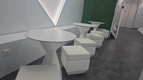 una fila de mesas y taburetes blancos en una habitación en Optimi Rooms Bilbao, en Bilbao