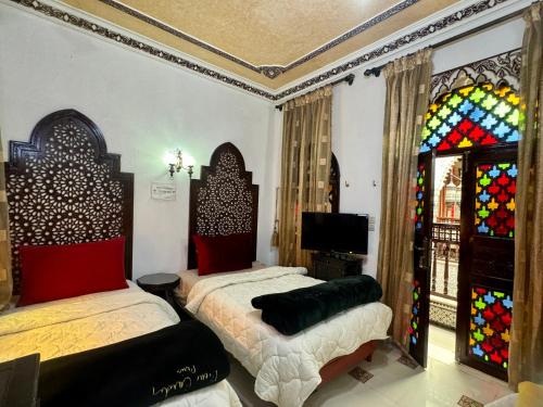 a bedroom with two beds and stained glass windows at Riad Mogador in Meknès