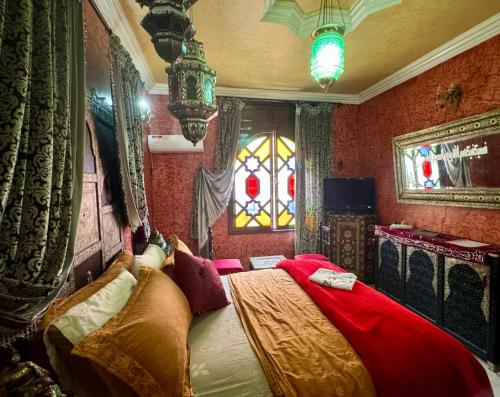a bedroom with a bed with red walls and a window at Riad Mogador in Meknès