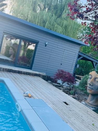 uma casa com uma piscina e um deque de madeira em le chant de la rivière em Abbeville
