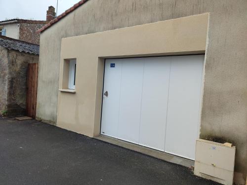uma porta de garagem branca do lado de um edifício em Maison de bourg équipée à 20mn du Puy du Fou - 4 pers em Bazoges-en-Paillers