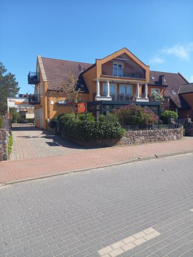 a house on a brick road next to a street at Willa Meander in Łeba