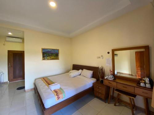 1 dormitorio con cama, tocador y espejo en Balkondes Karanganyar Borobudur en Borobudur