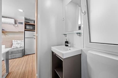 a small bathroom with a sink and a refrigerator at Mobile Homes Montepozzo, kamp Porton Biondi in Rovinj