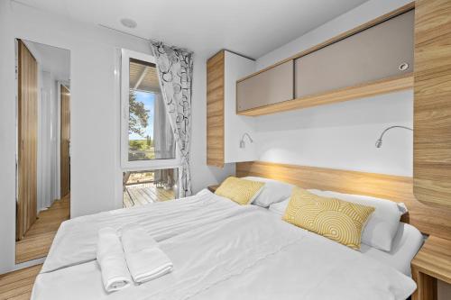 a bedroom with a large white bed with yellow pillows at Mobile Homes Montepozzo, kamp Porton Biondi in Rovinj