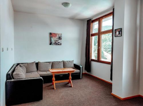 ein Wohnzimmer mit einem Sofa und einem Tisch in der Unterkunft Хотел Кючуковата Къща in Banite