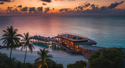 an aerial view of a resort on the beach at sunset at Sirru Fen Fushi Private Lagoon Resort Maldives in Shaviyani Atoll