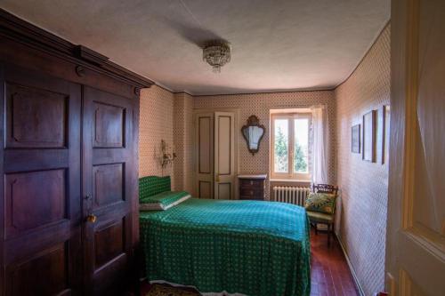 Un dormitorio con una cama verde y una ventana en La villa nel bosco, en Strona