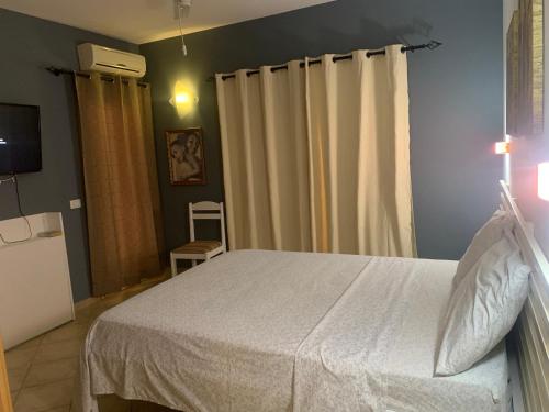 a bedroom with a white bed and curtains at Apartamento Antunes in Santa Maria