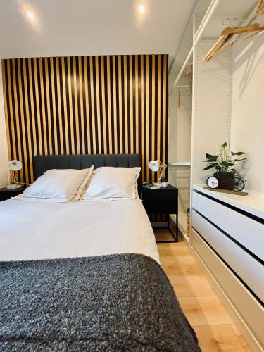 une chambre avec un grand lit avec une tête de lit en bois dans l'établissement Séjour Détente! Jacuzzi + Jardin privés, à Saint-Raphaël