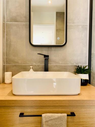 une salle de bain avec un lavabo blanc et un miroir dans l'établissement Séjour Détente! Jacuzzi + Jardin privés, à Saint-Raphaël